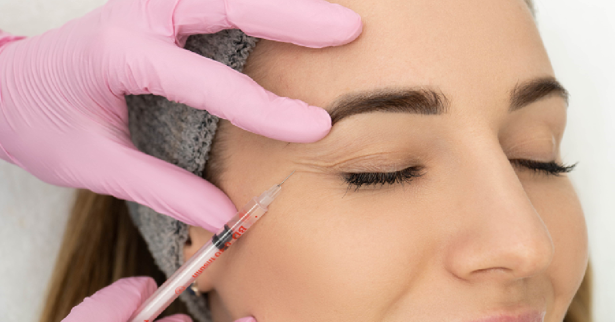 Close-up of a woman receiving a wrinkle relaxer injection near the eye area by a professional wearing pink gloves in Alpharetta, GA